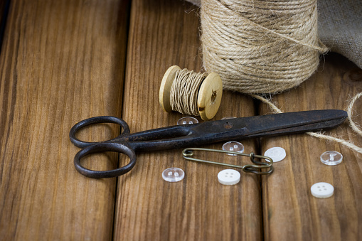 Close-up view of old sewing kit: scissors, twine, thread, buttons, on wooden background