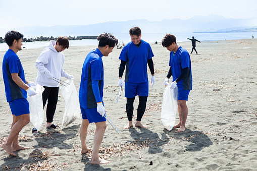 Young men beach soccer team.\nThey volunteer to clean up plastic bottles and trash on the beach.