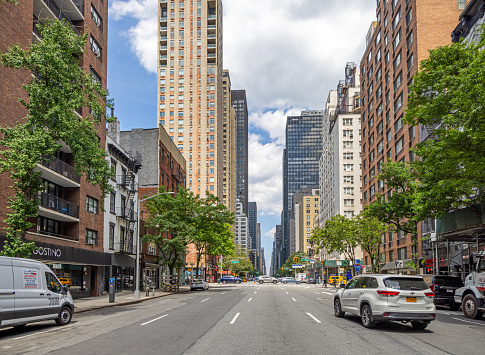 Manhattan, New York, NY, USA - July 9th 2022: View though Lexington Avenue with typical American big city architecture with high rise residential buildings and green trees