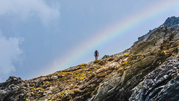 istock Hiker solo walking along the high mountain trail with rainbow 1419828208