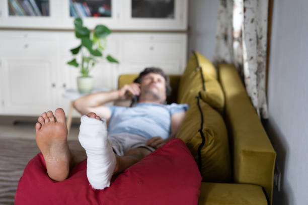 homme allongé sur le canapé après avoir eu un accident et s’est cassé la jambe - lying down men isolated young adult photos et images de collection