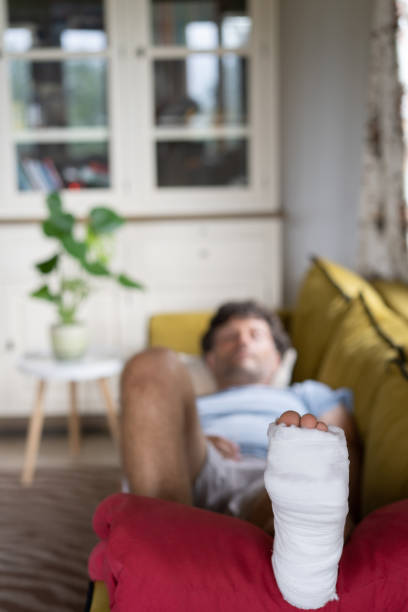 l’homme se détend à la maison, ayant une jambe cassée - lying down men isolated young adult photos et images de collection