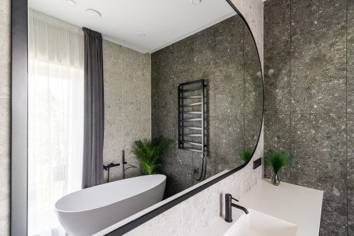 Modern and stylish bathroom with large mirror and bathtub.