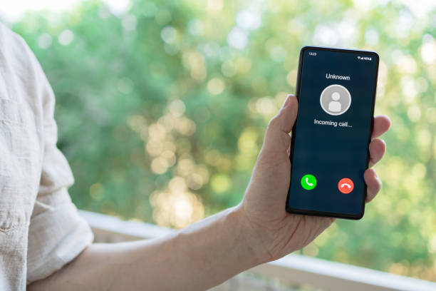 istock Man standing outside and holding a smartphone with incoming call display on screen. 1419836181