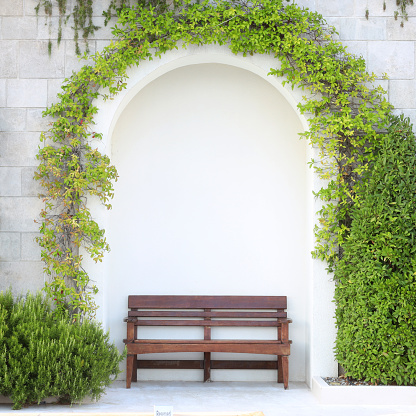 This is a bench under an arch with hanging plants.