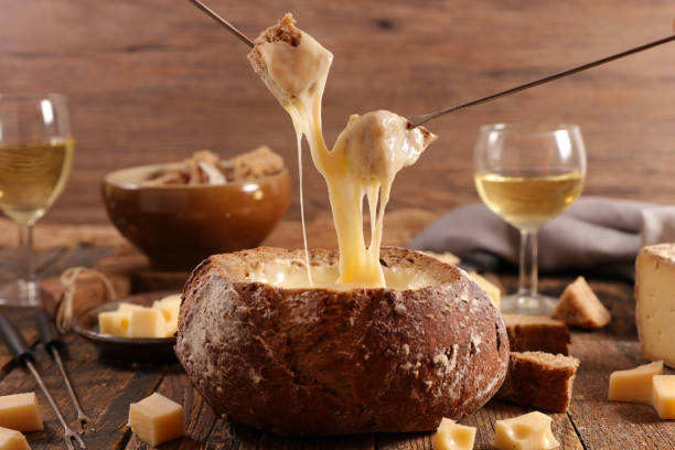 Traditional Swiss cheese fondue with wine glasses stock photo