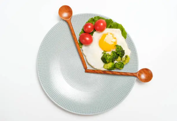 Photo of Healthy food and wooden spoons on a plate on white background top view, intermittent fasting concept.