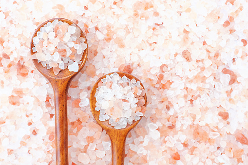 Two wooden spoons with pink himalayan salt close up, copy space.