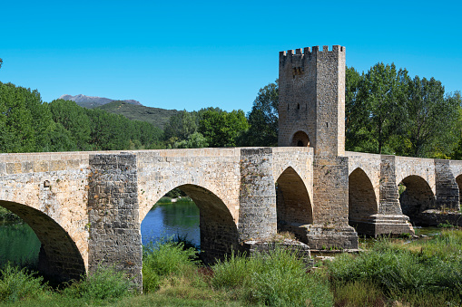 View of the medieval bridge of Roman origin with fifteenth-century fortified tower over the Ebro River as it passes through the town of Frías, Spain