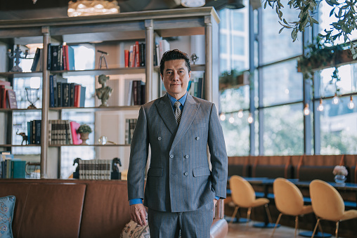 Portrait Asian Chinese successful businessman looking at camera smiling standing at luxury hotel lobby