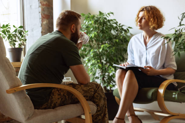 istock Young distressed man in military uniform talking to psychologist during therapy session, indoors. Help, support, ptsd, health and harmony concept 1419848297