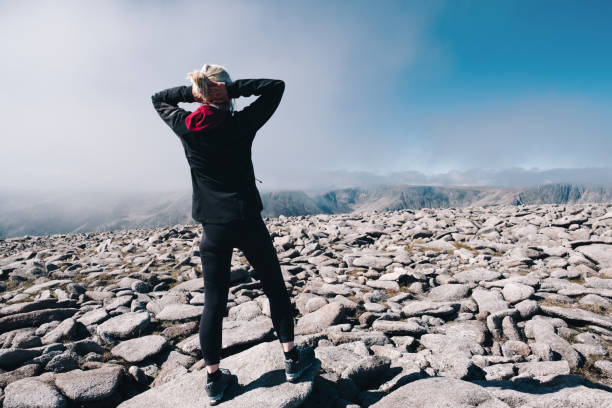 Woman standing on the boulder field at the summit plateau on Ben MacDui near the resort of Aviemore, Scotland, in summer.