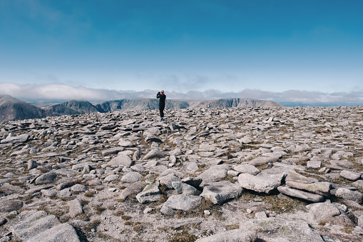 Woman standing on the boulder field at the summit plateau on Ben MacDui near the resort of Aviemore, Scotland, in summer.
