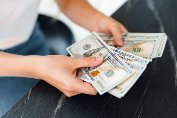istock Close up of female hands counting dollar banknotes 1419854154