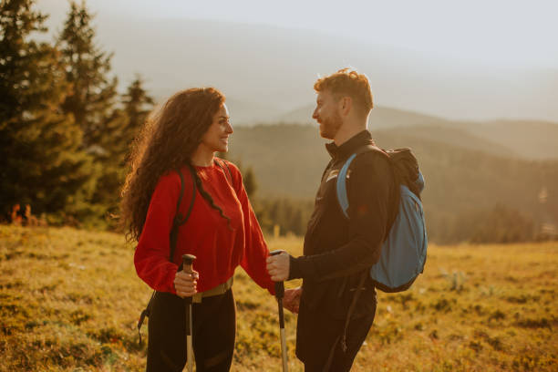 istock Smiling couple walking with backpacks over green hills 1419854813