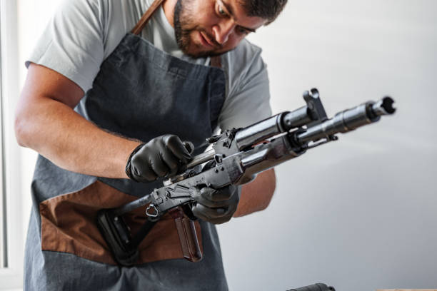 istock Close up of young man in apron disassembling a gun above the table 1419855046