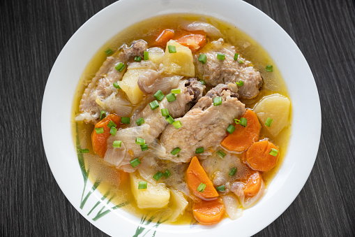 A bowl of chicken wing stew with potatoes and carrots.
