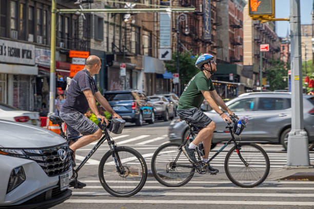 Manhattan, New York, NY, USA - July 10th 2022: Two mature male tourists on bike in traffic on Delancey Street
