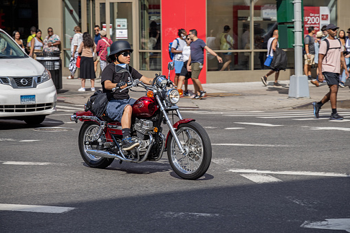 Manhattan, New York, NY, USA - July 14th 2022: Man on a classic motorbike with crash helmet and goggles in the intersection between the Bowery and Canal Street