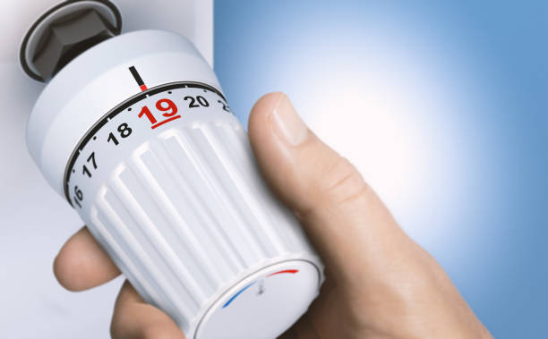 Man reducing energy consumption by setting thermostat temperature to 19 degrees. Man reducing energy consumption by setting thermostat temperature to 19 degrees. Close up on a knob. Composite image between a 3d illustration and a hand photography. 18 19 years stock pictures, royalty-free photos & images