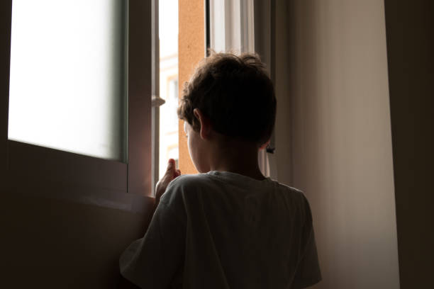 teenage looking out window Unrecognizable adolescent looking out window small boys stock pictures, royalty-free photos & images