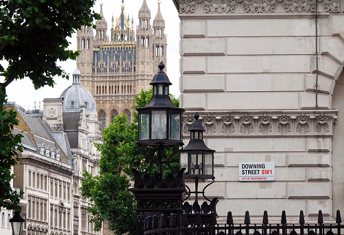 London, UK - June 24, 2022: Downing Street sign on the wall of a building with the Houses of Parliament in the background, London, UK