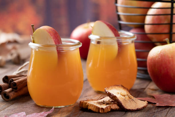 Glass of apple cider with autumn background Glass of apple cider with apple slices on wooden table and autumn background apple juice photos stock pictures, royalty-free photos & images