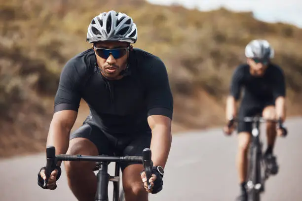 Photo of Training, energy and fitness with cyclists exercise on bicycle outdoors, practice speed and endurance. Athletes riding together, prepare for marathon or competition while enjoying cardio workout