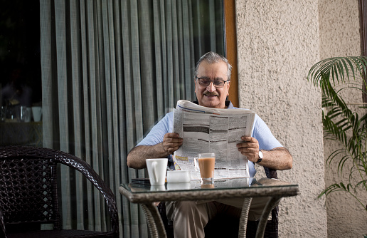 Senior Man Reading Newspaper At Home