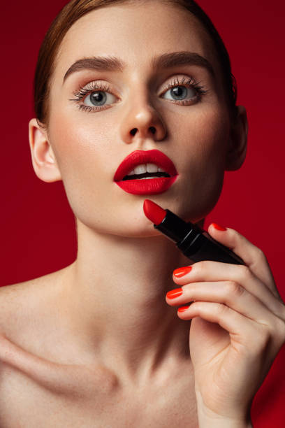 istock Beautiful emotional woman with bright make-up applying red lipstick 1419873785