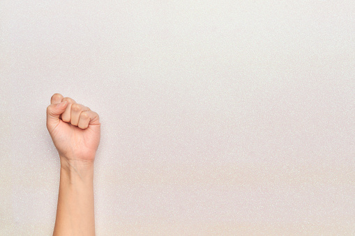 woman's fist raised up revolution feminist fight on glitter white background with copy space horizontal