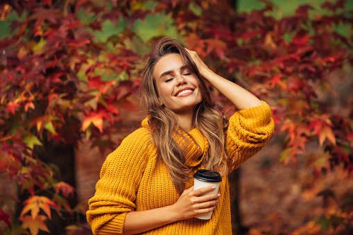 Autumn photo of a beautiful girl holding coffee