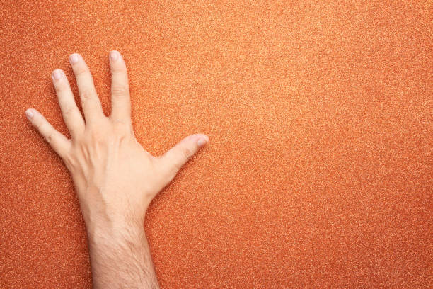 istock man hand upside down on glitter orange background 1419877240