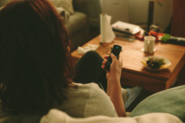 Woman with remote control watching tv stock photo