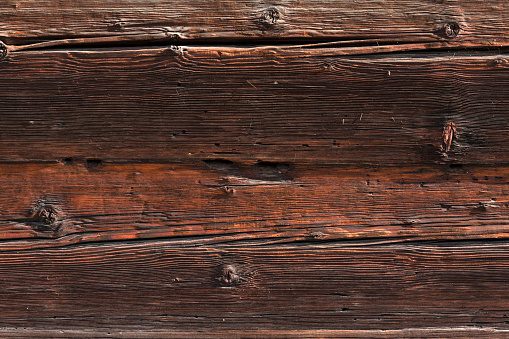 Old and weathered dark brown cracked wood beam surface with nice rough grain texture.  Wooden church beam texture.