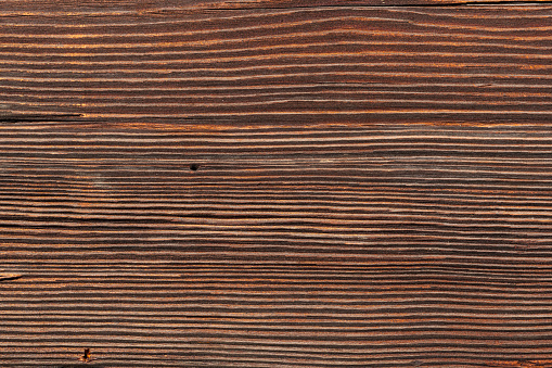 Old and weathered dark brown cracked wood beam surface with nice rough grain texture.  Wooden church beam texture.