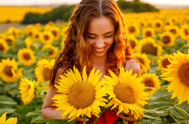 istock Cute young woman is holding sunflower in her hand while 1419887582