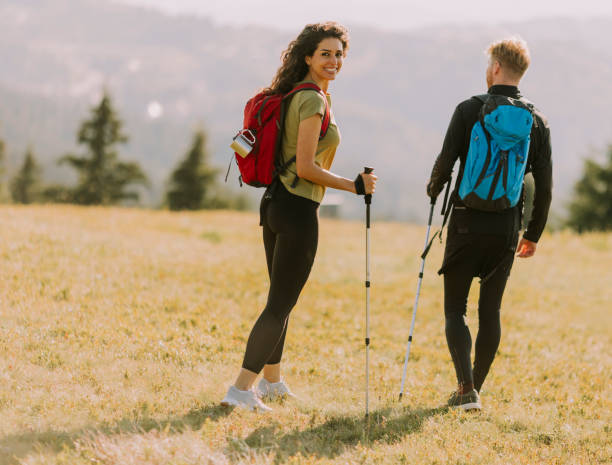 istock Smiling couple walking with backpacks over green hills 1419888046