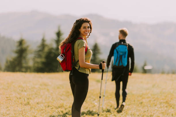 istock Smiling couple walking with backpacks over green hills 1419888075