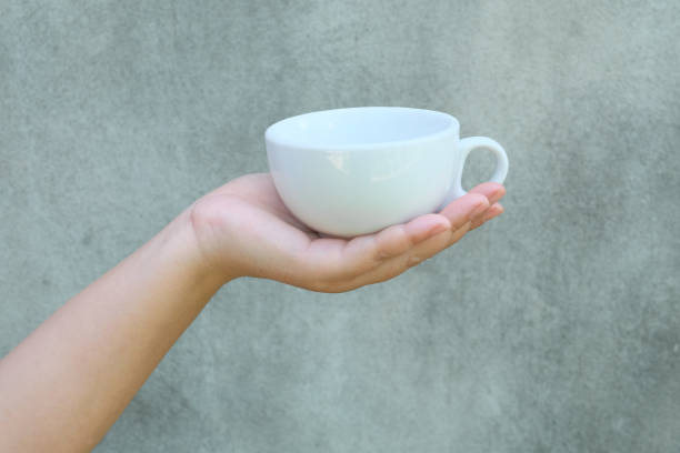 istock hand holding a cup of coffee on wall background. 1419889351