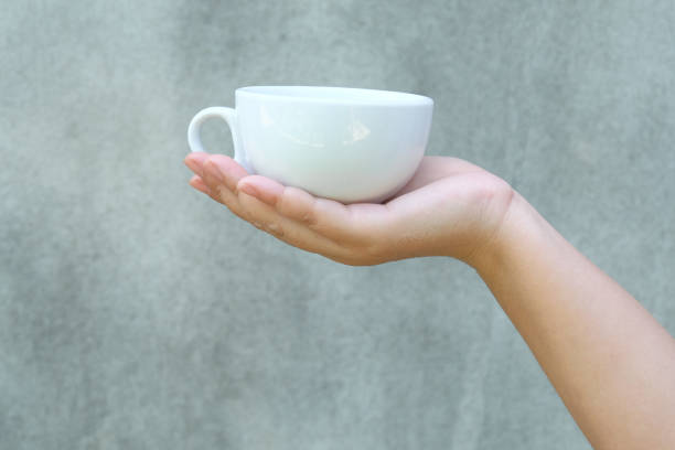 istock hand holding a cup of coffee on wall background. 1419889441