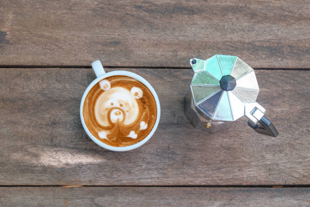 Latte art with moka pot on wood background.