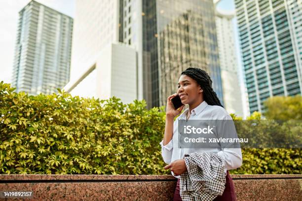 Smiling young Miami businesswoman outdoors using phone