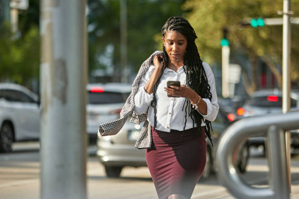 istock Businesswoman checking smart phone while walking downtown 1419892225