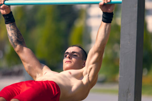 Workout. Strong muscular man, student training, practicing at sport ground at public park in summer morning, outdoors. Action, skills, challenges and achievements concept. Closeup