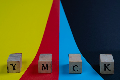 YMCK color space. The letters Y, M, C and K on a wooden towels over a yellow, red, cyan and black background