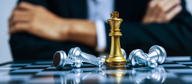 Business strategy. golden king with silver chess piece on chess board game competition on business man background, checkmate, chess battle, victory, success, leadership, teamwork, team leader concept