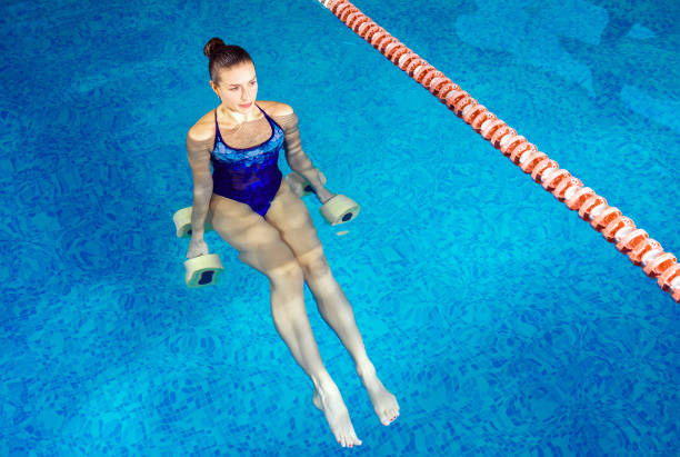 屋内プールで水エアロビクスをしている若い女性、スポーツのコンセプト - 水治療 ストックフォトと画像