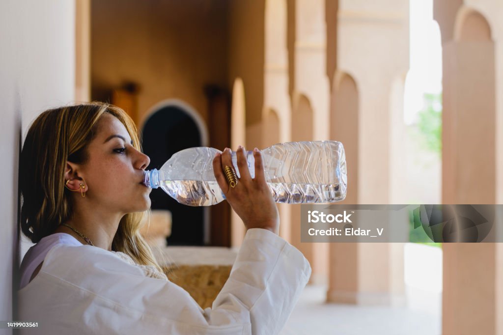 woman drinking water Latin woman sitting drinking water in a meditation area of a Morocco’s palace. Active Lifestyle Stock Photo