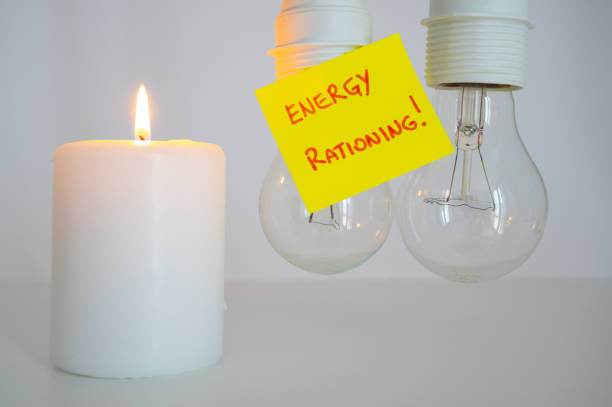 Lit candle, and unlit bulbs. Energy saving and rationing. stock photo
